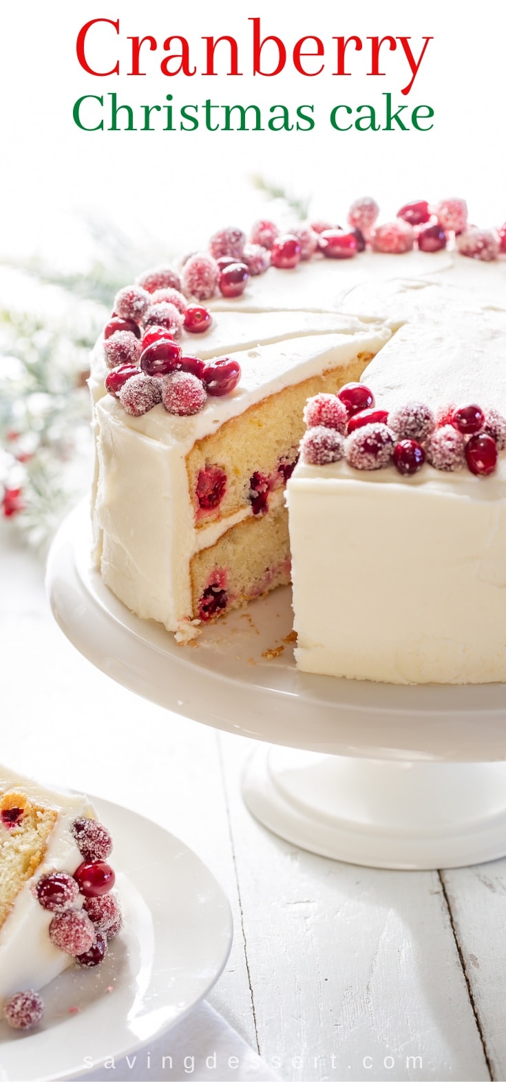 An orange and cranberry layer cake on a cake stand sliced showing the inside layers