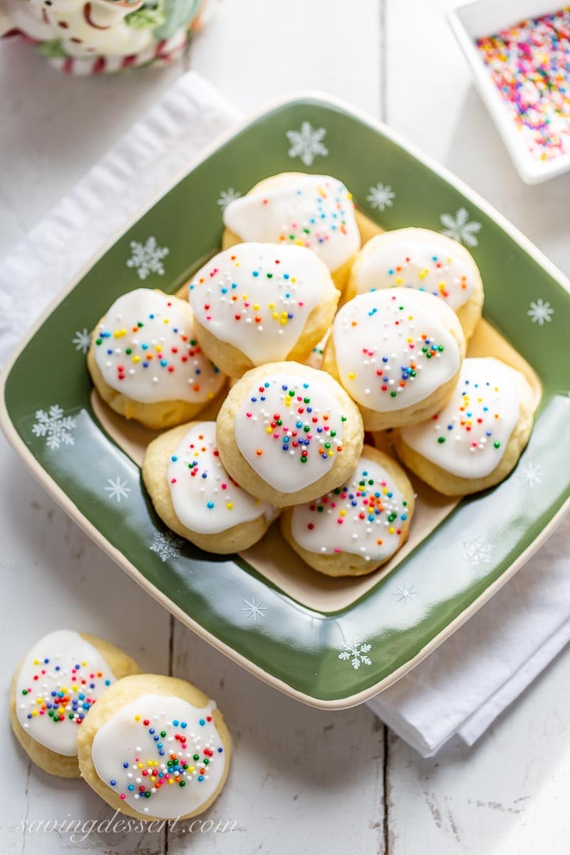 An overhead view of a holiday plate of soft vanilla and lemon cookies with a lemon icing and sprinkles