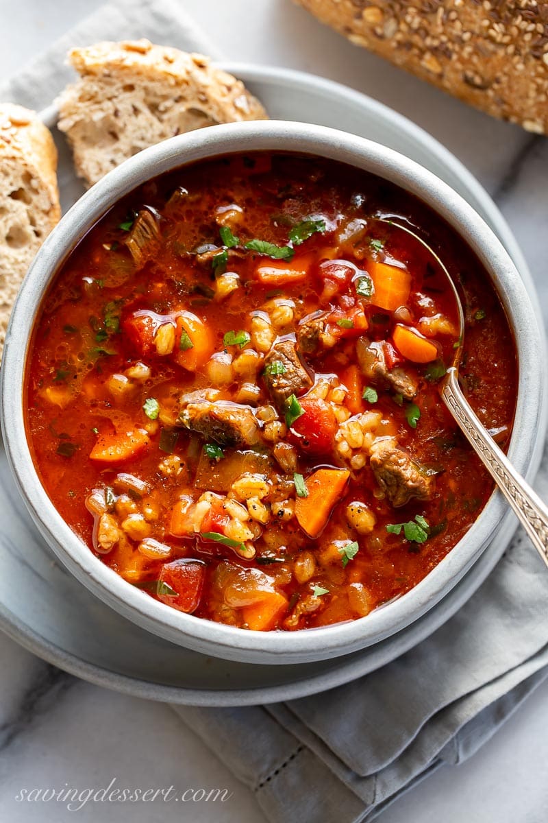 A bowl of soup with a spoon served with crust bread