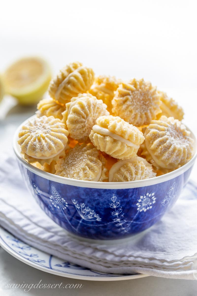 A blue bowl of lemon cookies filled with lemon cream