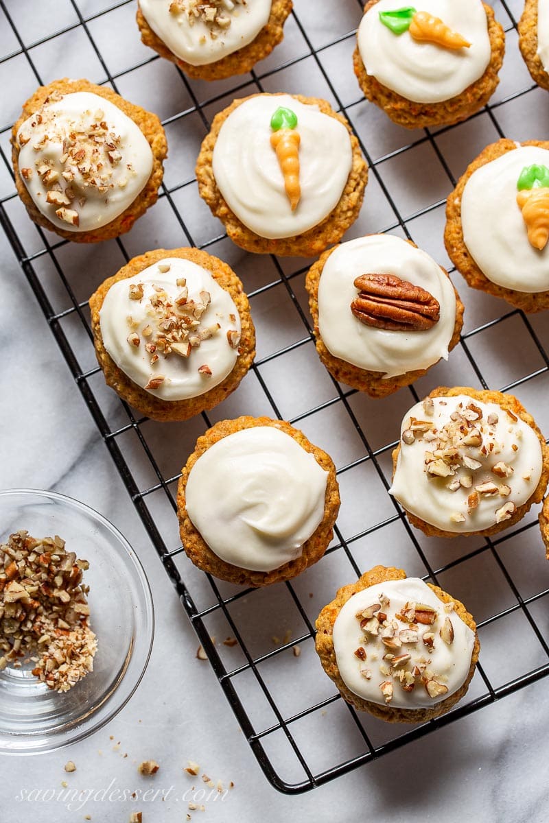 A cooking rack covered with iced cookies with nut and carrots