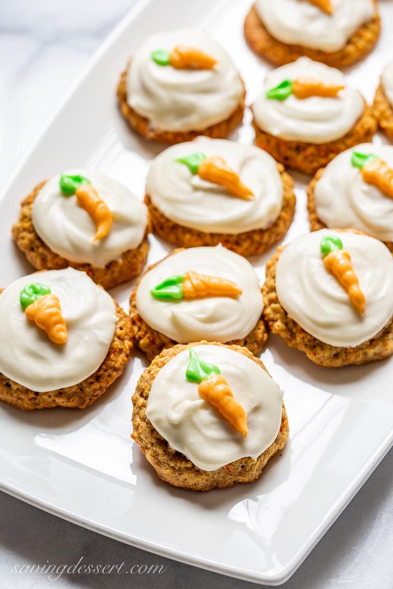 A platter of cookies topped with icing and decorated with piped carrots in orange and green