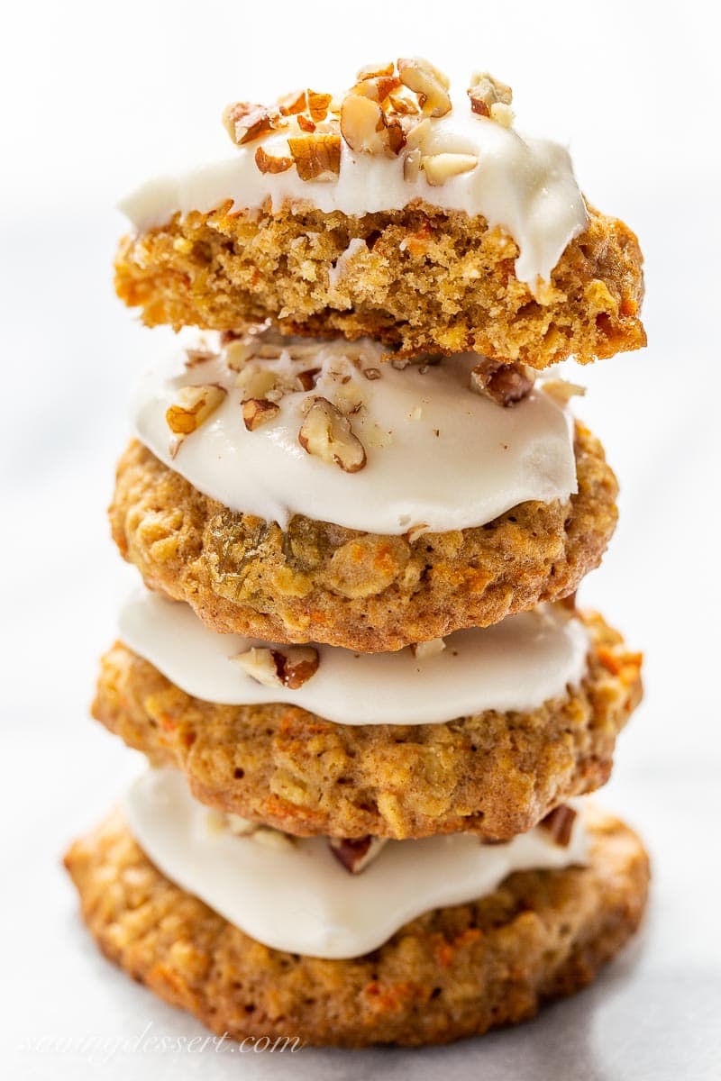 A stack of carrot cake cookies topped with icing and chopped nuts