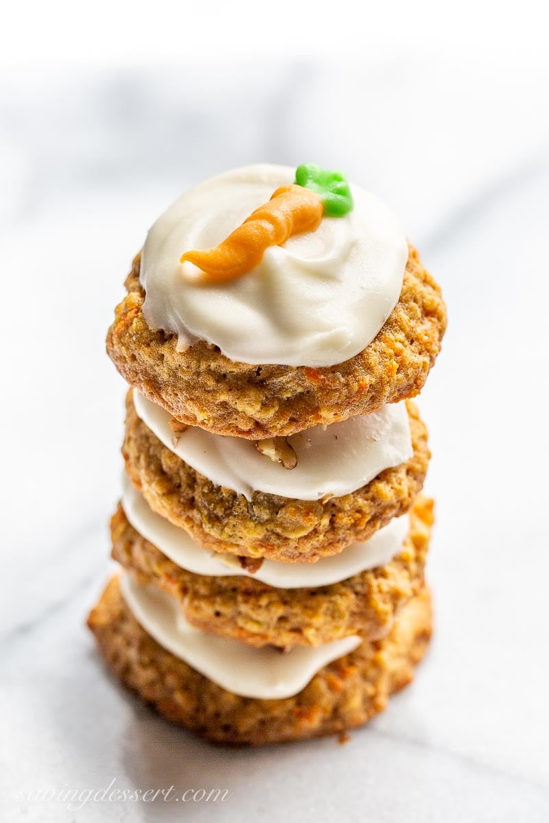 Carrot cake cookies with icing in a stack and decorated with a piped carrot