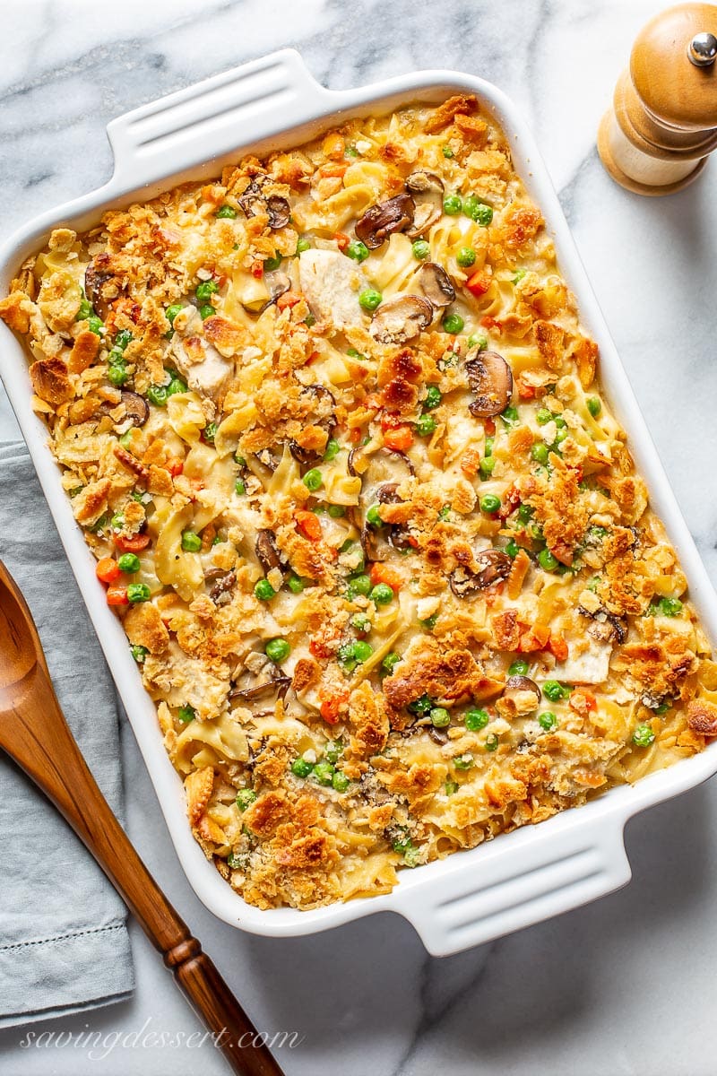 A casserole dish filled with chicken, mushrooms, peas, carrots and noodles