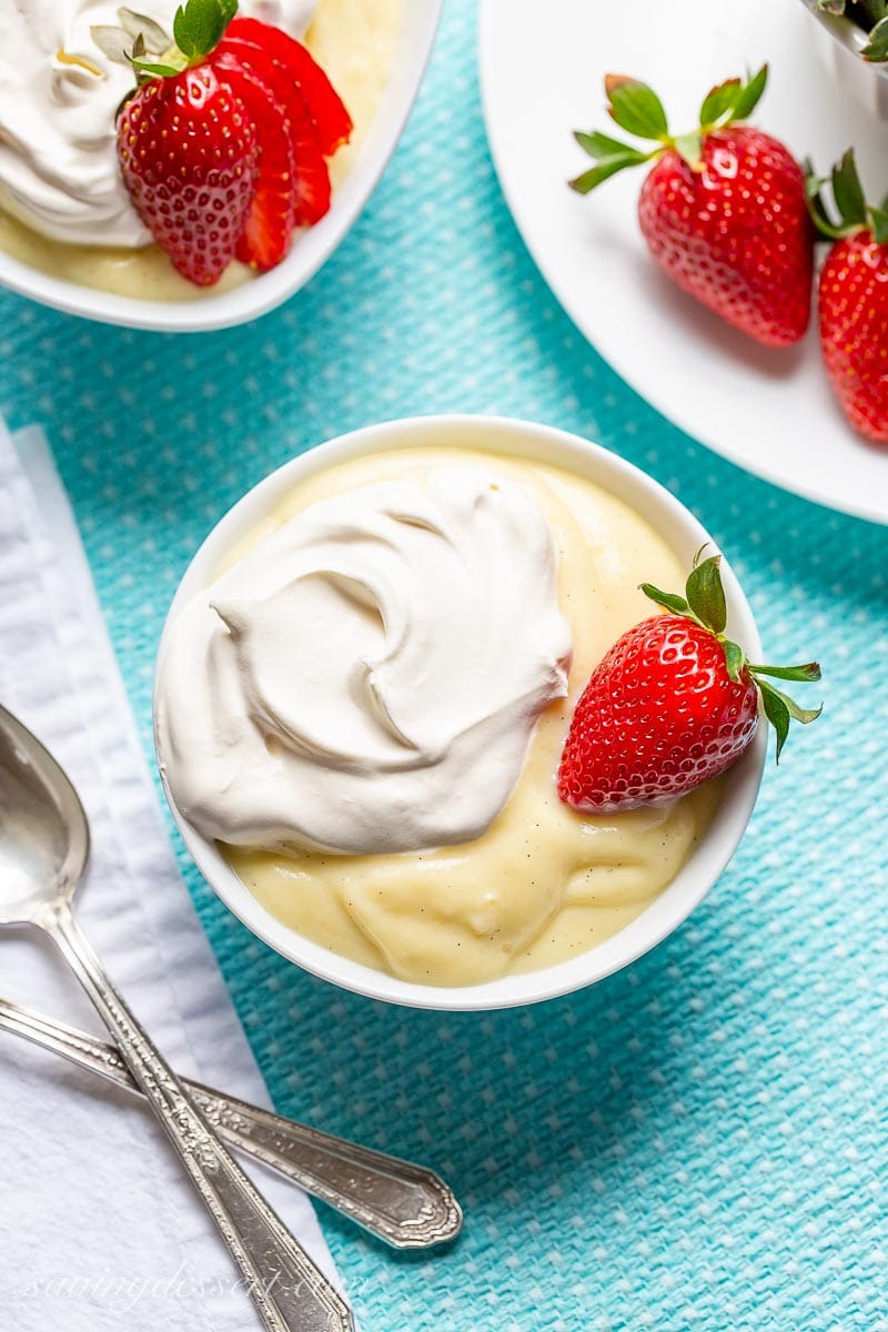 An overhead view of a bowl of homemade vanilla pudding topped with whipped cream and strawberries