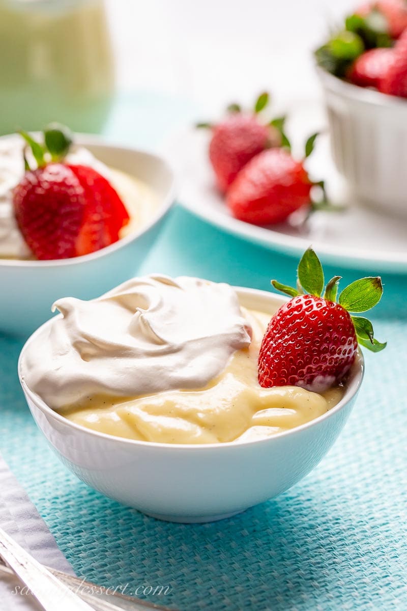 A small bowl of pudding, whipped cream and strawberries