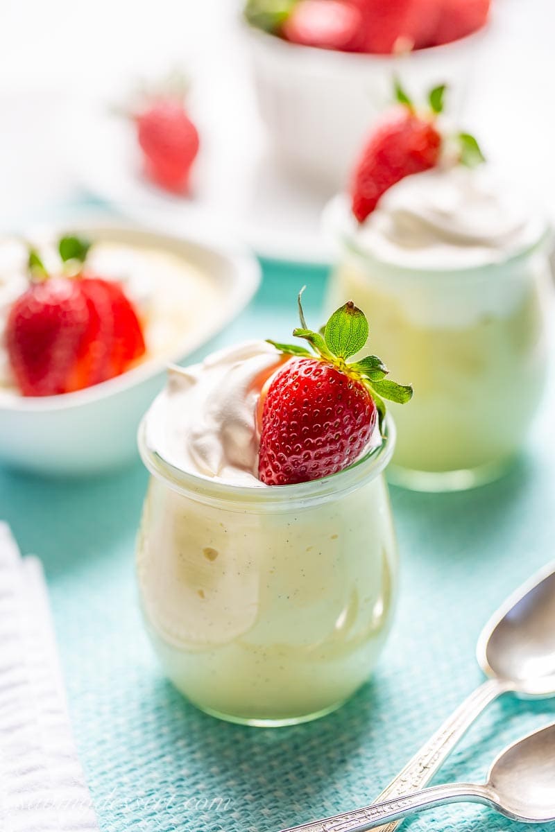 A jar of vanilla pudding topped with whipped cream and a ripe whole strawberries