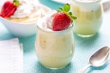 Homemade vanilla pudding in a jar topped with a strawberry
