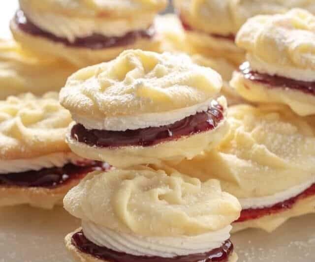 A stack of butter cookies filled with jam and buttercream icing