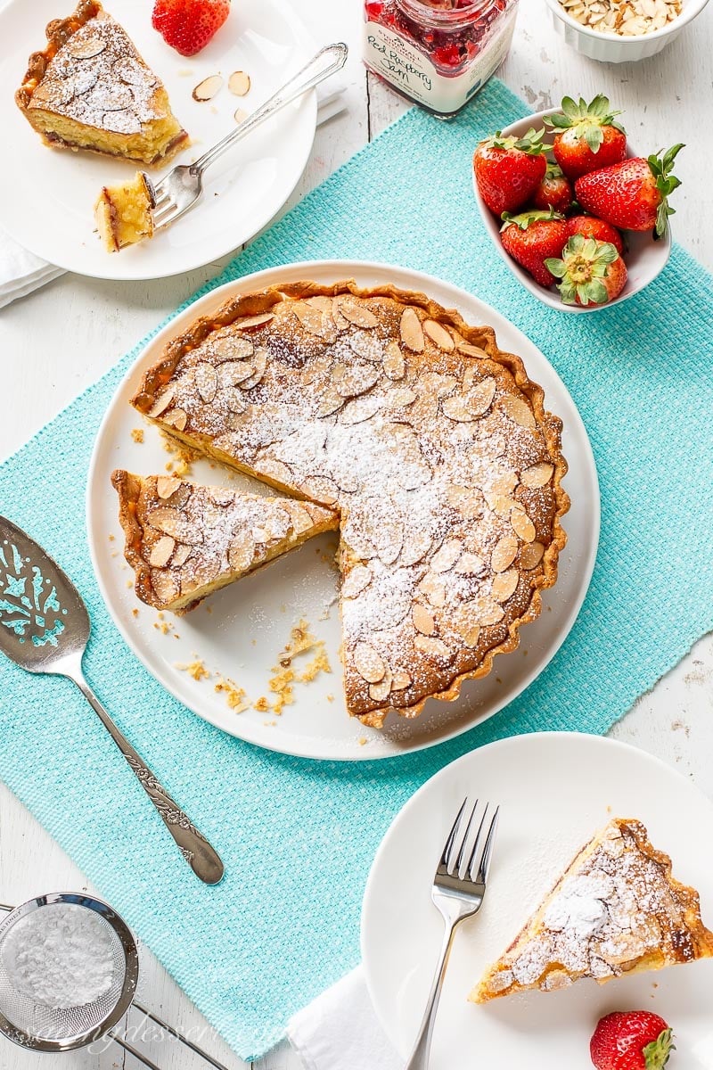 A table set with a pie topped with almonds and served with strawberries