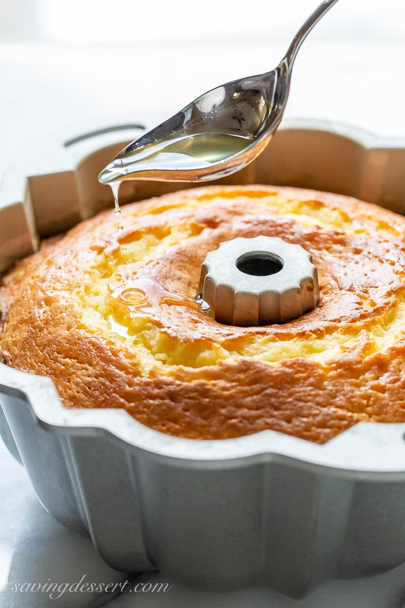 A cake in a Bundt pan being drizzled with lemon syrup