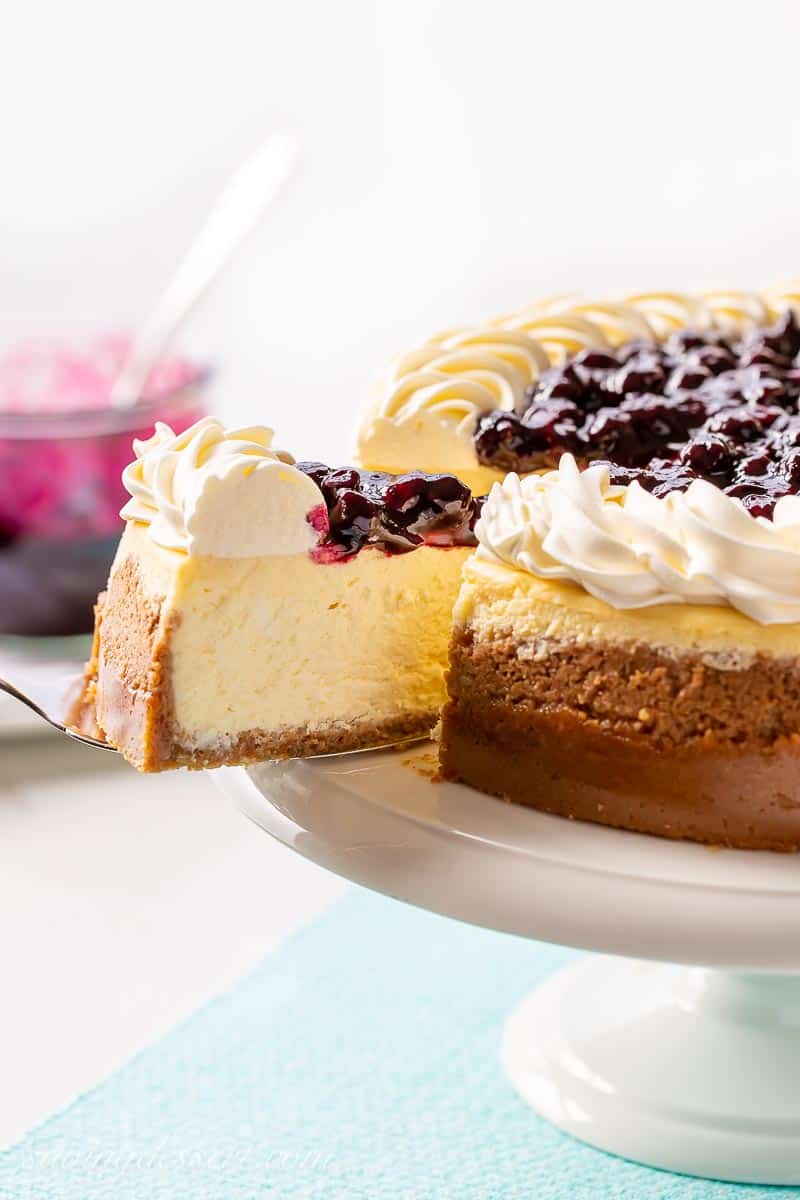 A slice of lemony cheesecake topped with whipped cream and blueberry sauce