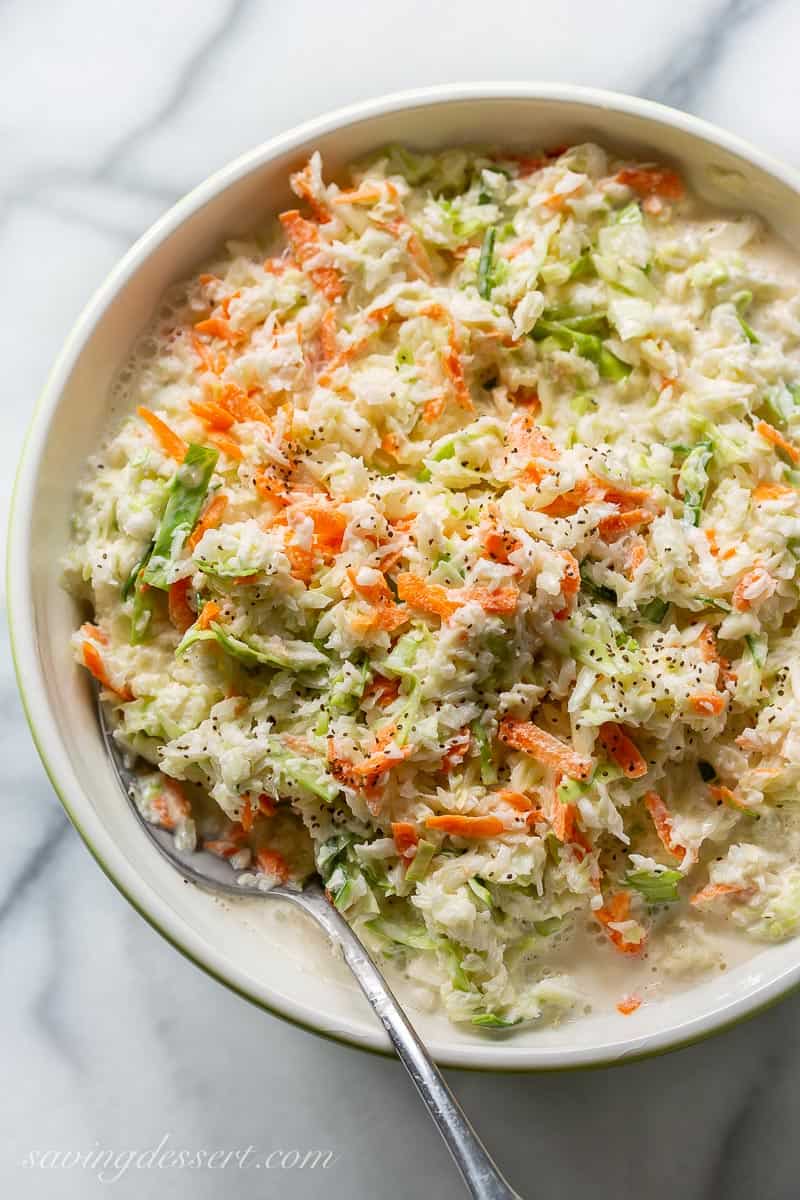 A bowl of creamy coleslaw with a spoon