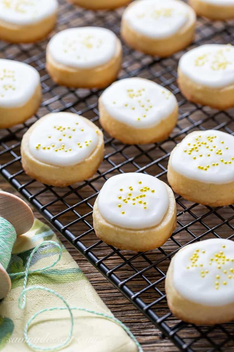 Cookies on a cooling rack iced with a lemon glaze and yellow sprinkles