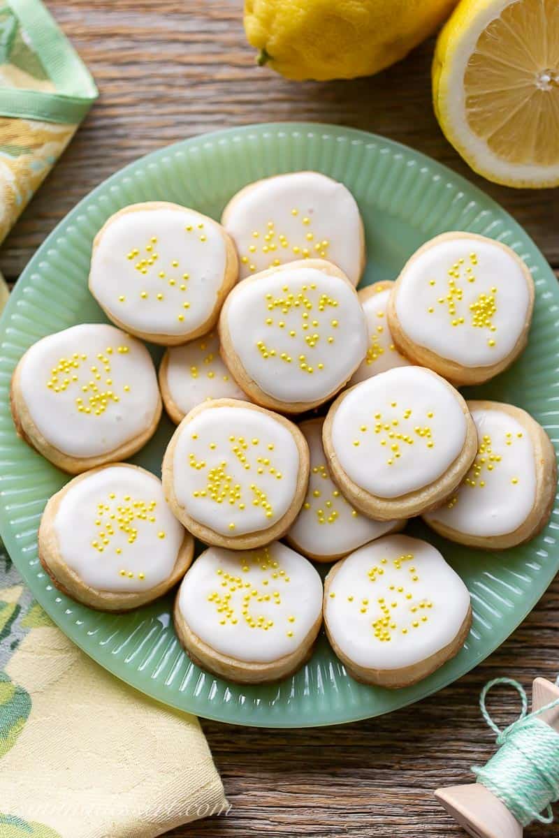 A green plate filled with Lemon Shortbread Cookies with icing and sprinkles