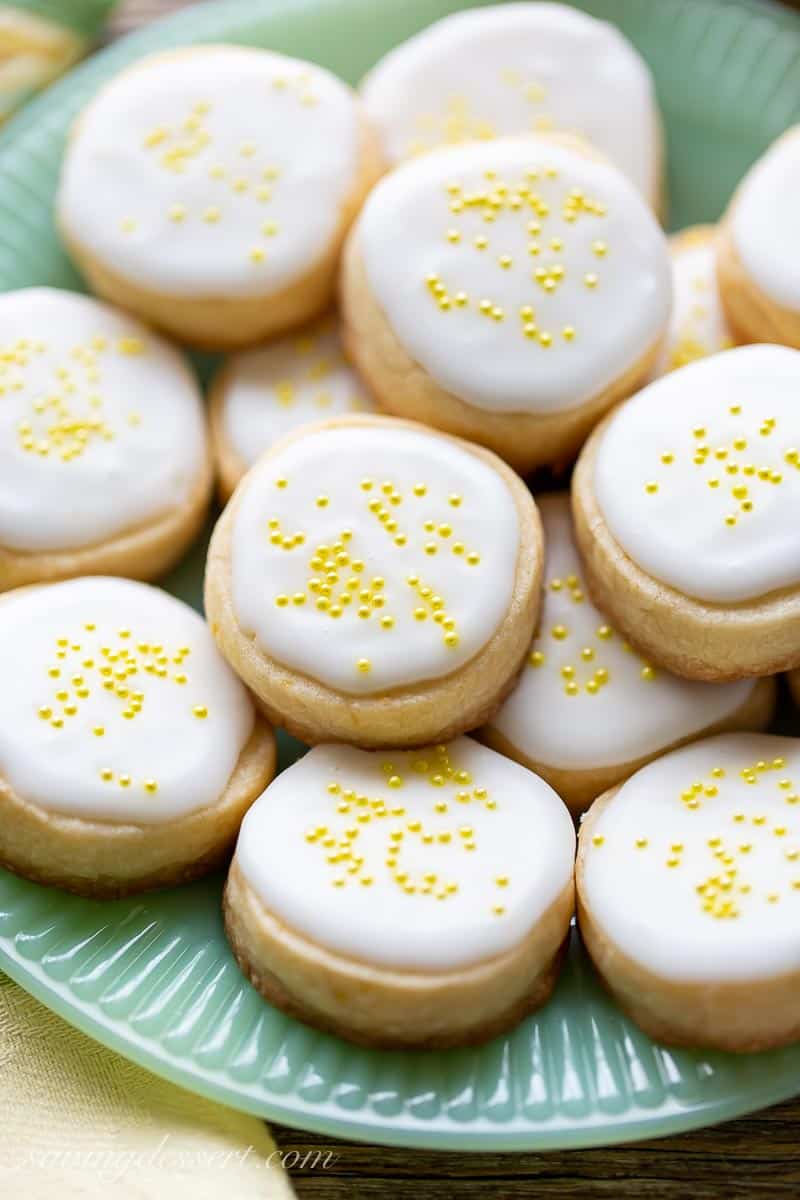 a closeup of a plate of lemon cookies topped with icing and sprinkles