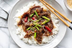 Overhead view of a plate of homemade Mongolian Beef with green onions and red arbol chiles