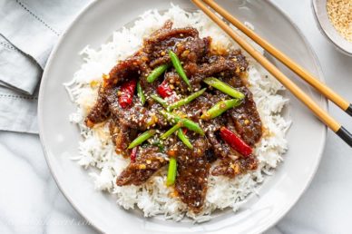 Overhead view of a plate of homemade Mongolian Beef with green onions and red arbol chiles