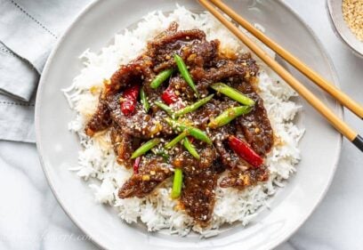 Overhead view of a plate of homemade Mongolian Beef with green onions and red arbol chiles