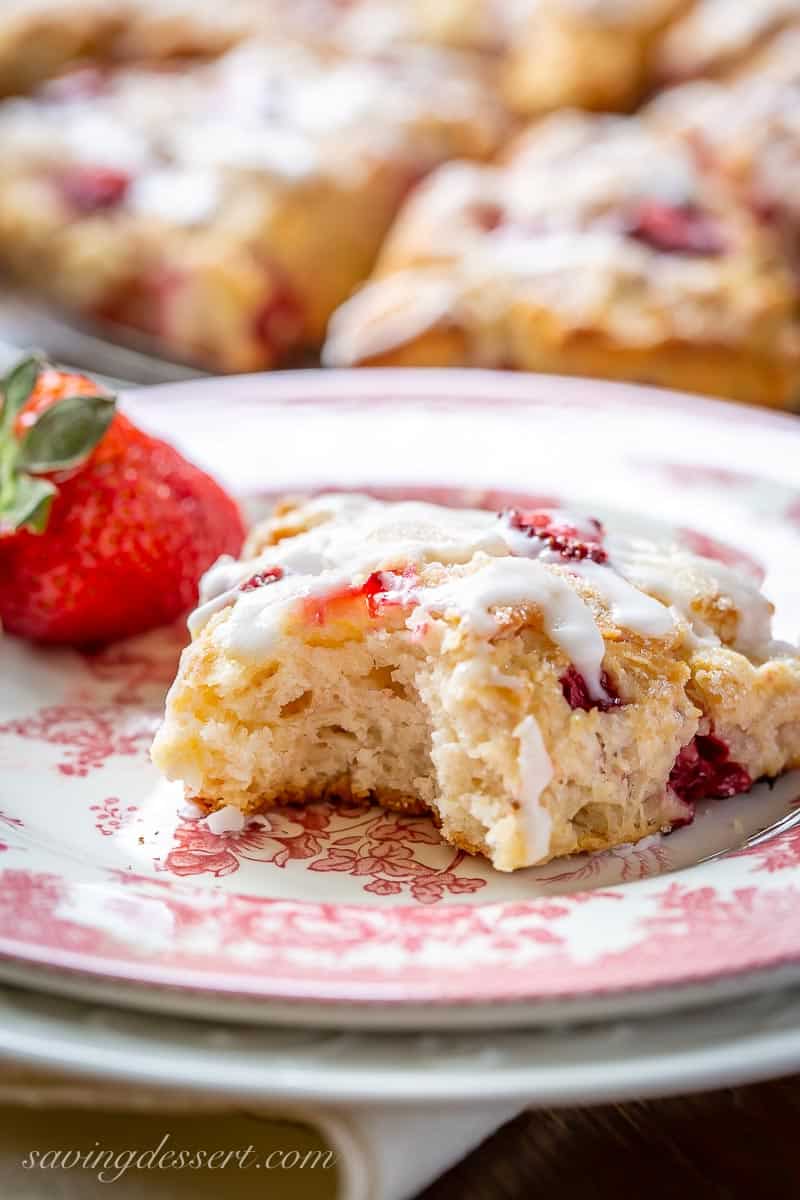 A strawberry scone with a bit out of the middle showing a soft airy inside