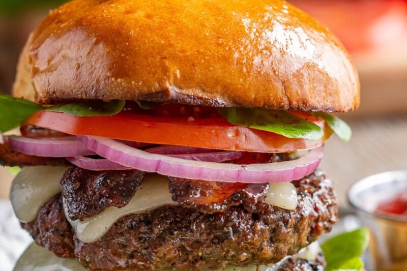 A double decked marinated butter with lettuce, onion, tomato and french fries on the side.