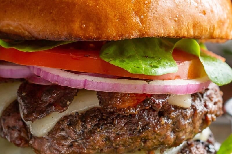 A close up of a grilled marinated hamburger with all the trimmings.