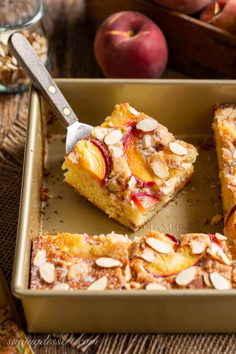 A piece of simple peach cake on a spatula in a pan