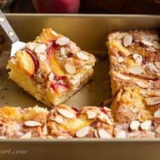 Sliced peach cake in a pan topped with almonds