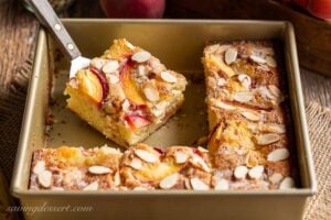 Sliced peach cake in a pan topped with almonds