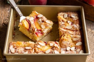 Sliced peach cake in a pan topped with almonds