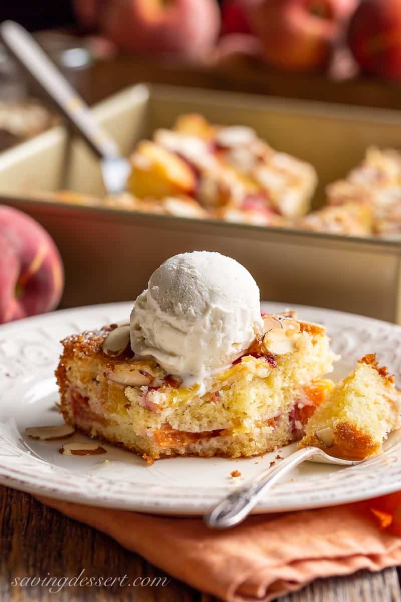 A piece of peach cake topped with almonds and ice cream