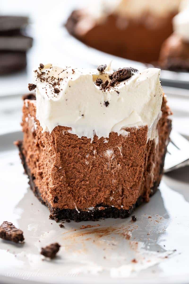 Close up photo of a piece of chocolate icebox pie topped with whipped cream and crushed Oreo cookies