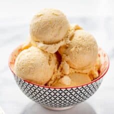 A small bowl with scoops of mango ice cream and a spoon