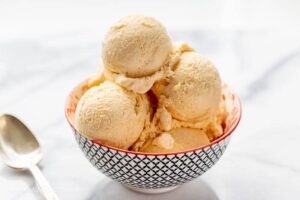 A small bowl with scoops of mango ice cream and a spoon