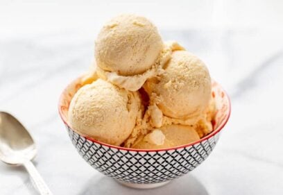 A small bowl with scoops of mango ice cream and a spoon