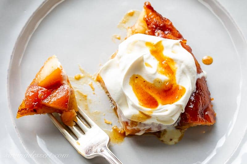 Overhead view of a slice of caramel pear tart topped with whipped cream and a drizzle of caramel