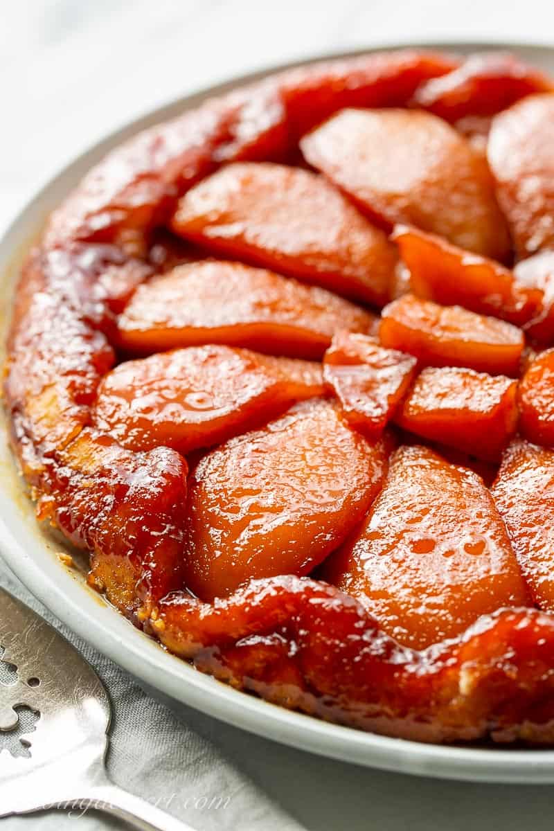 A pear tart on a platter with dark amber caramel