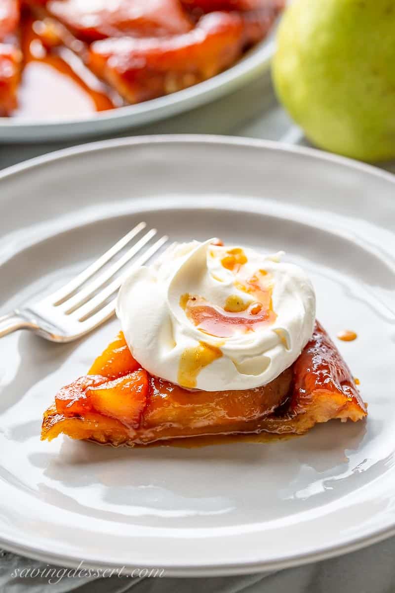 A slice of pear tarte tatin topped with whipped cream