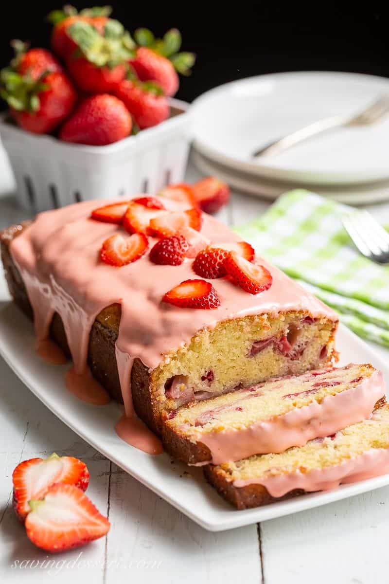 A sliced loaf of strawberry bread topped with fresh strawberries