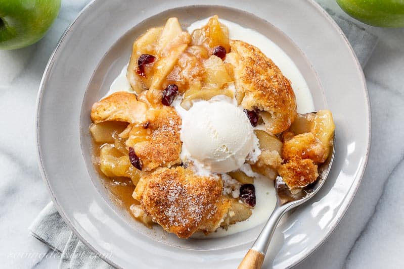 A bowl of juicy apple cobbler topped with melting ice cream
