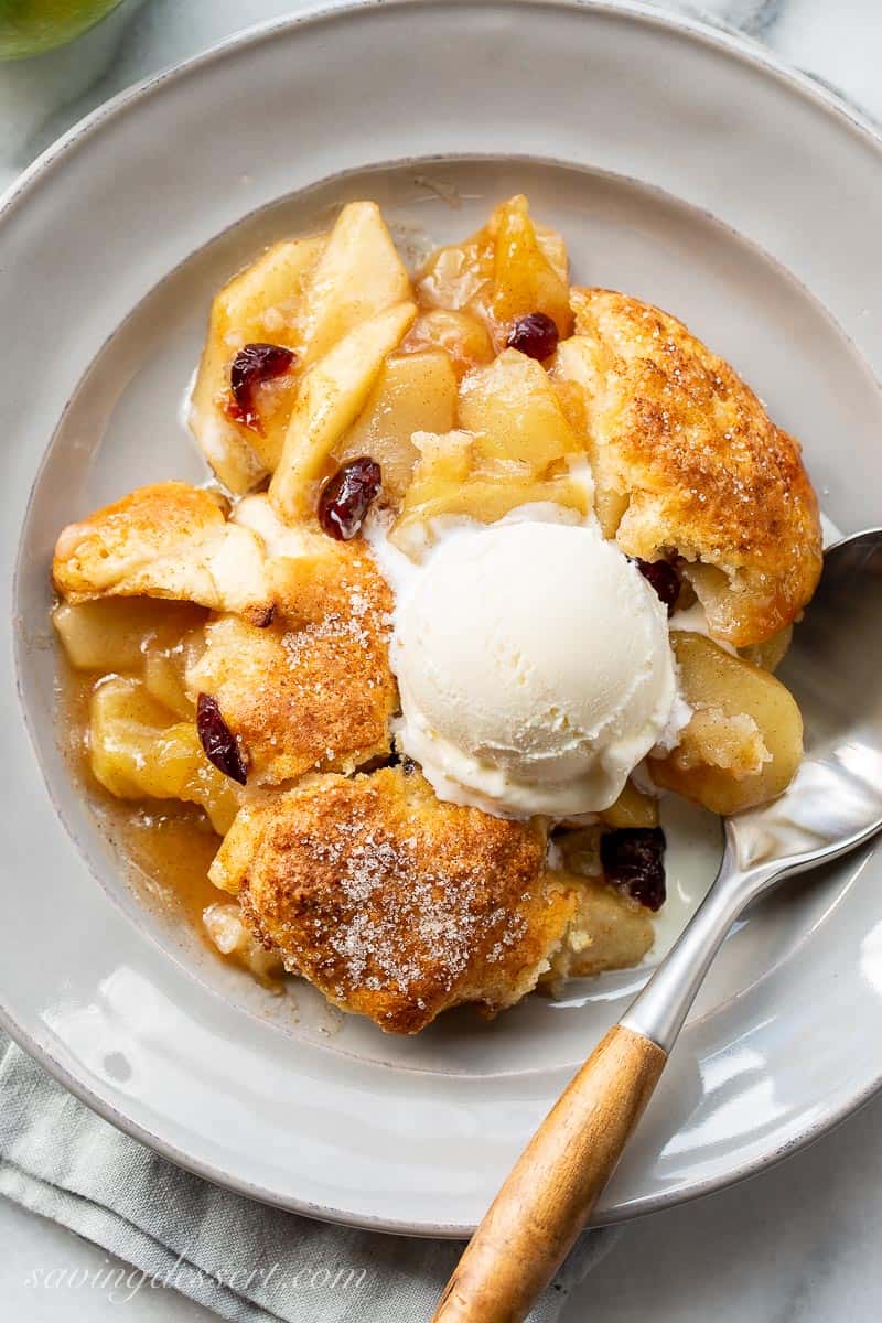 Apple cobbler on a plate with a scoop of ice cream and a spoon