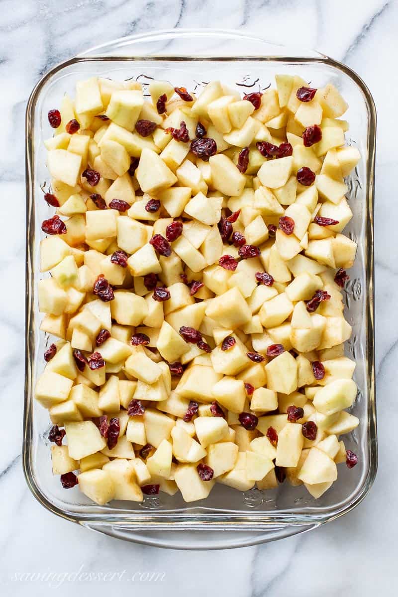 A casserole dish filled with diced apples and dried cranberries