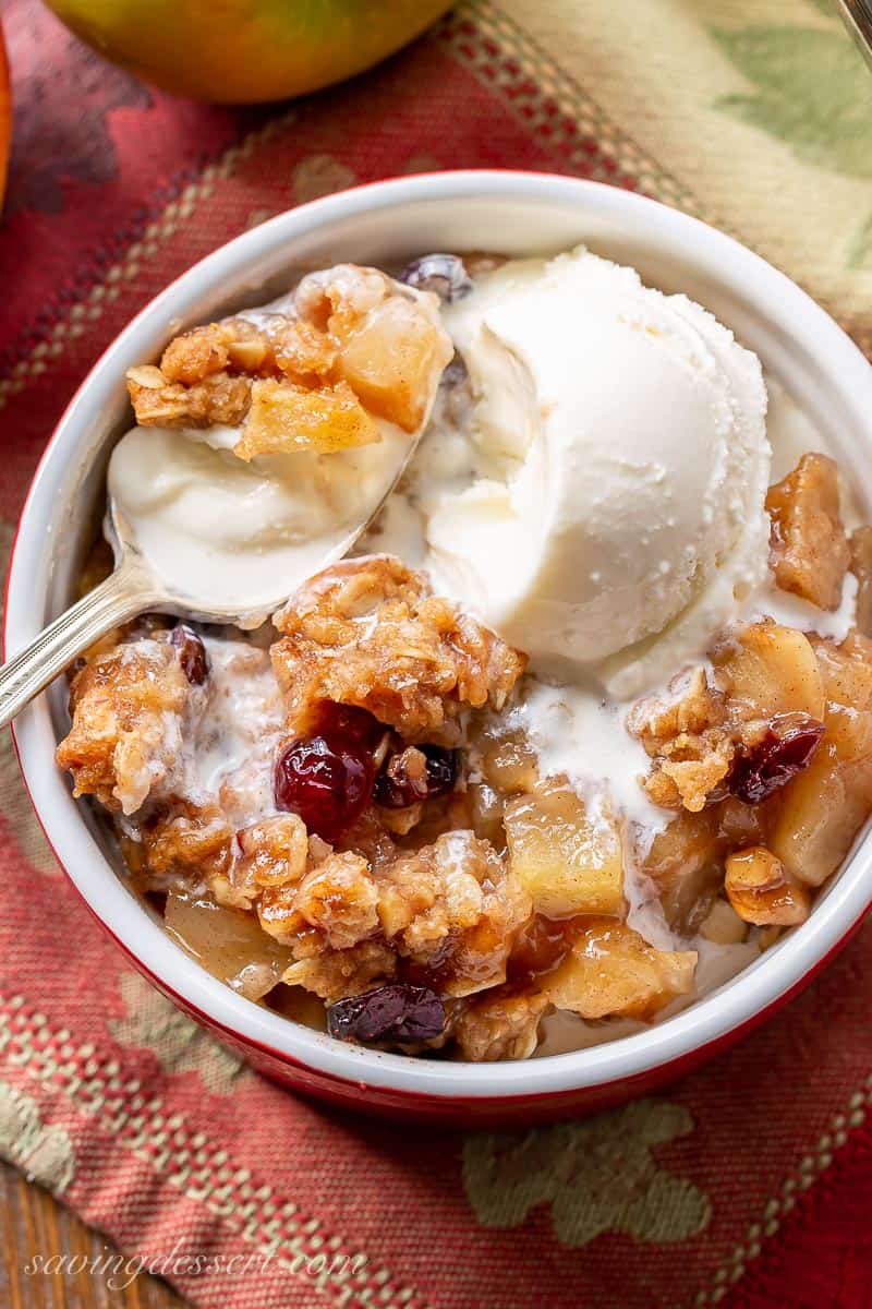 Overhead view of a bowl of apple crisp topped with a scoop of melting ice cream