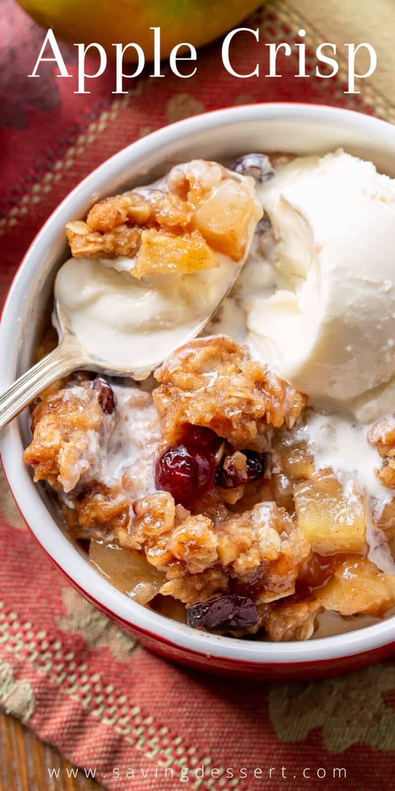 An overhead view of a bowl of apple crisp topped with melting vanilla ice cream