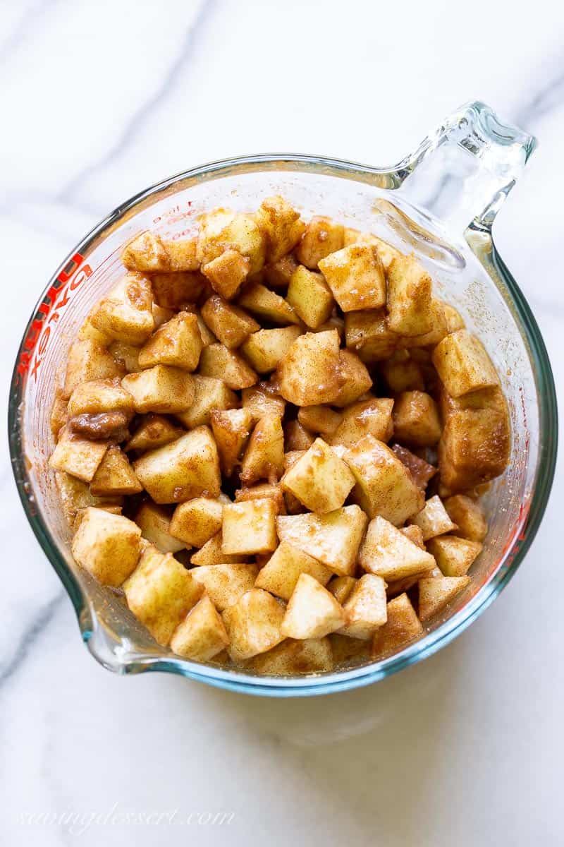 A mixing bowl filled with diced apples in cinnamon and sugar