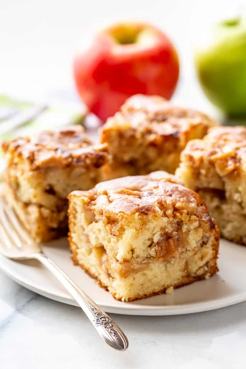 A plate filled with pieces of apple fritter cake with an apple in the background