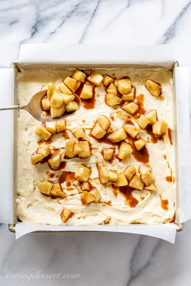 A square cake pan filled with cake batter and diced cinnamon apples
