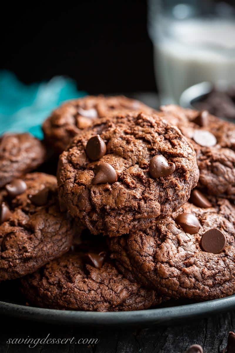 Soft and fudgy chocolate cookies topped with chocolate chips on a black plate