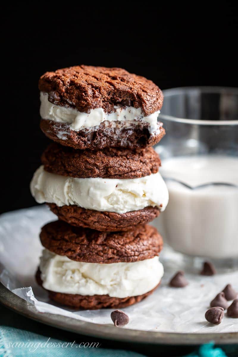 A stack of three homemade ice cream sandwiches and a glass of milk on the side